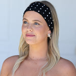 Woman wearing a black polka dot headband against a light gray background