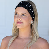 Woman wearing a black polka dot headband against a light gray background