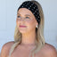 Woman wearing a black polka dot headband against a light gray background