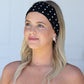 Woman wearing a black polka dot headband against a light gray background