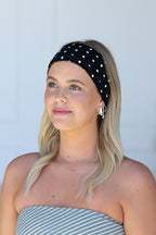 Woman wearing a black polka dot headband against a light gray background