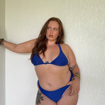 Woman wearing a blue bikini against a plain wall