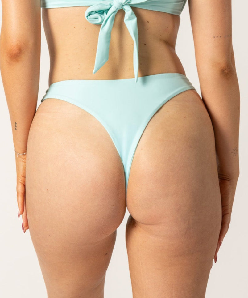 Woman wearing a light blue bikini set on a plain background